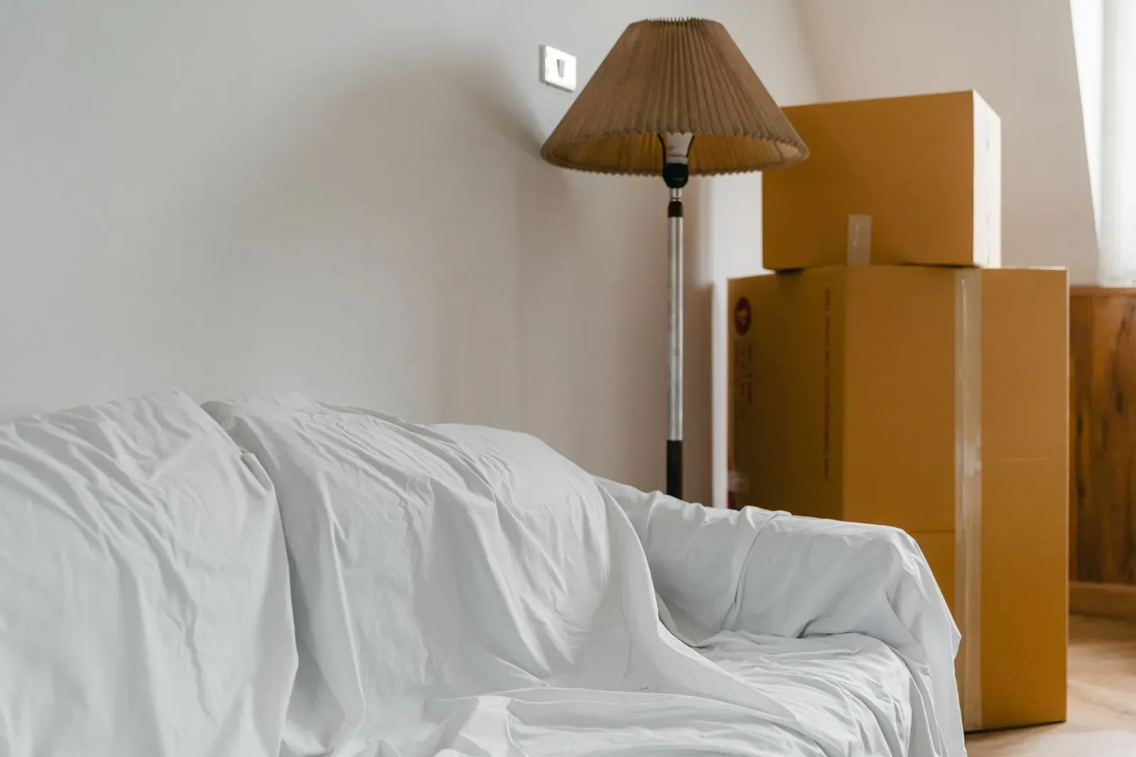 Covered sofa and boxes in a room being packed up for a move