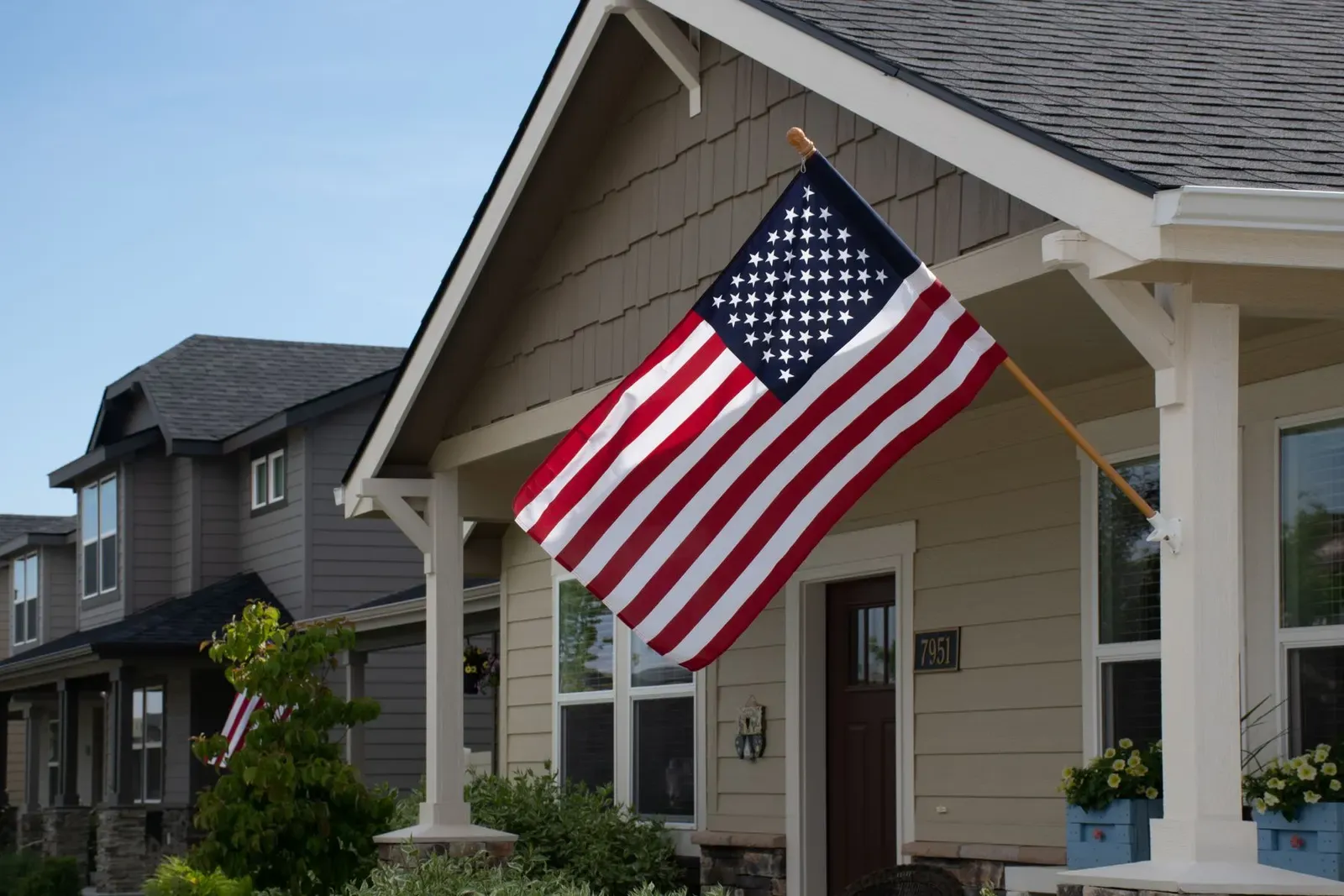 American flag flying from the front porch of a neighborhood home