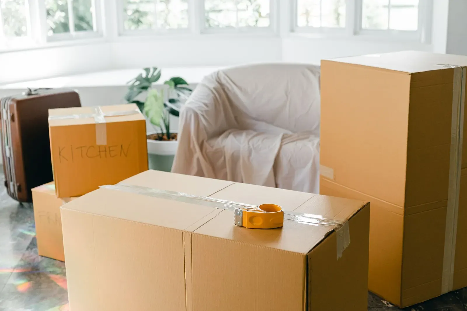 Packed boxes and a suitcase in a sunny room of a house being prepared for a move