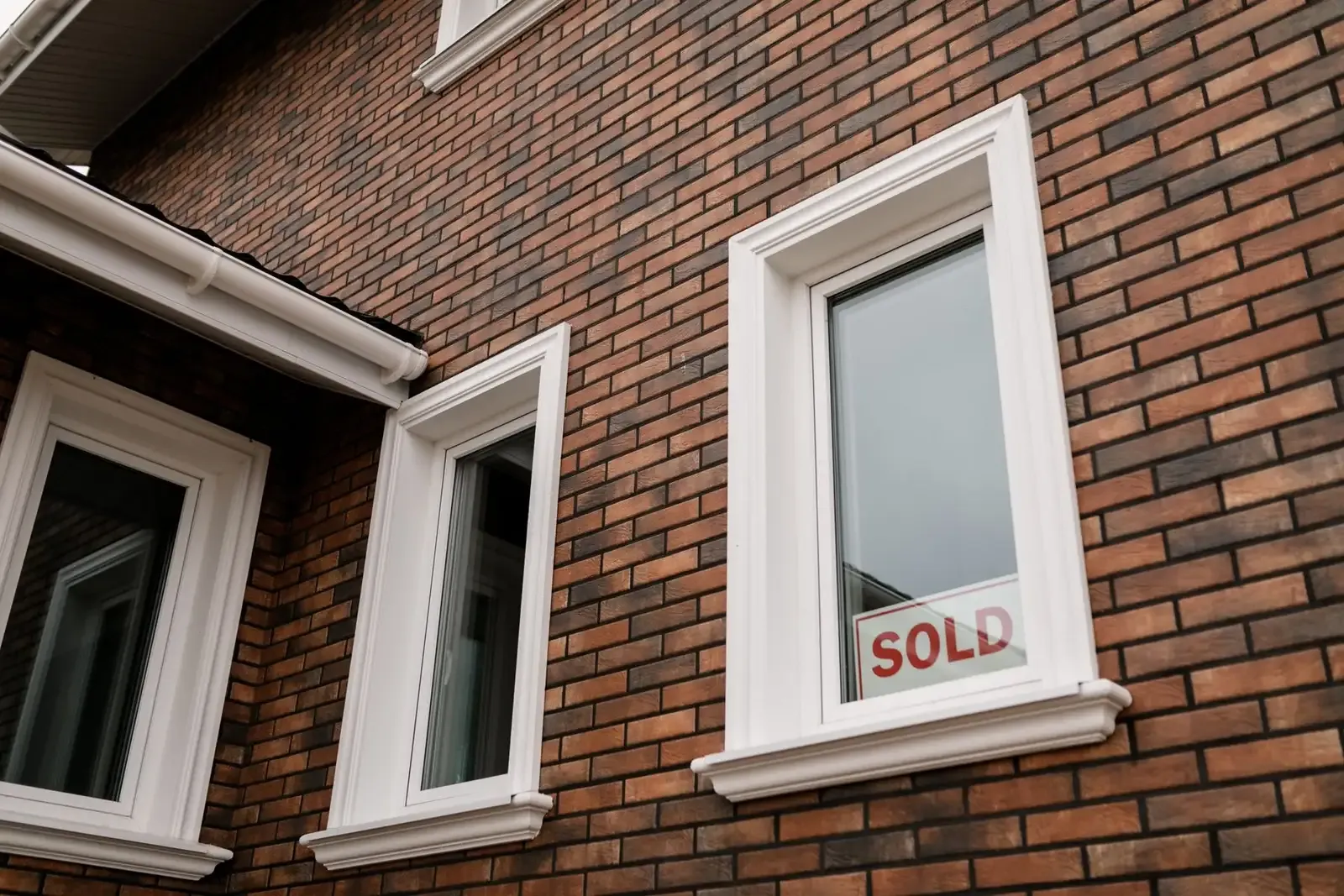 Brick home with a sold sign in a front window
