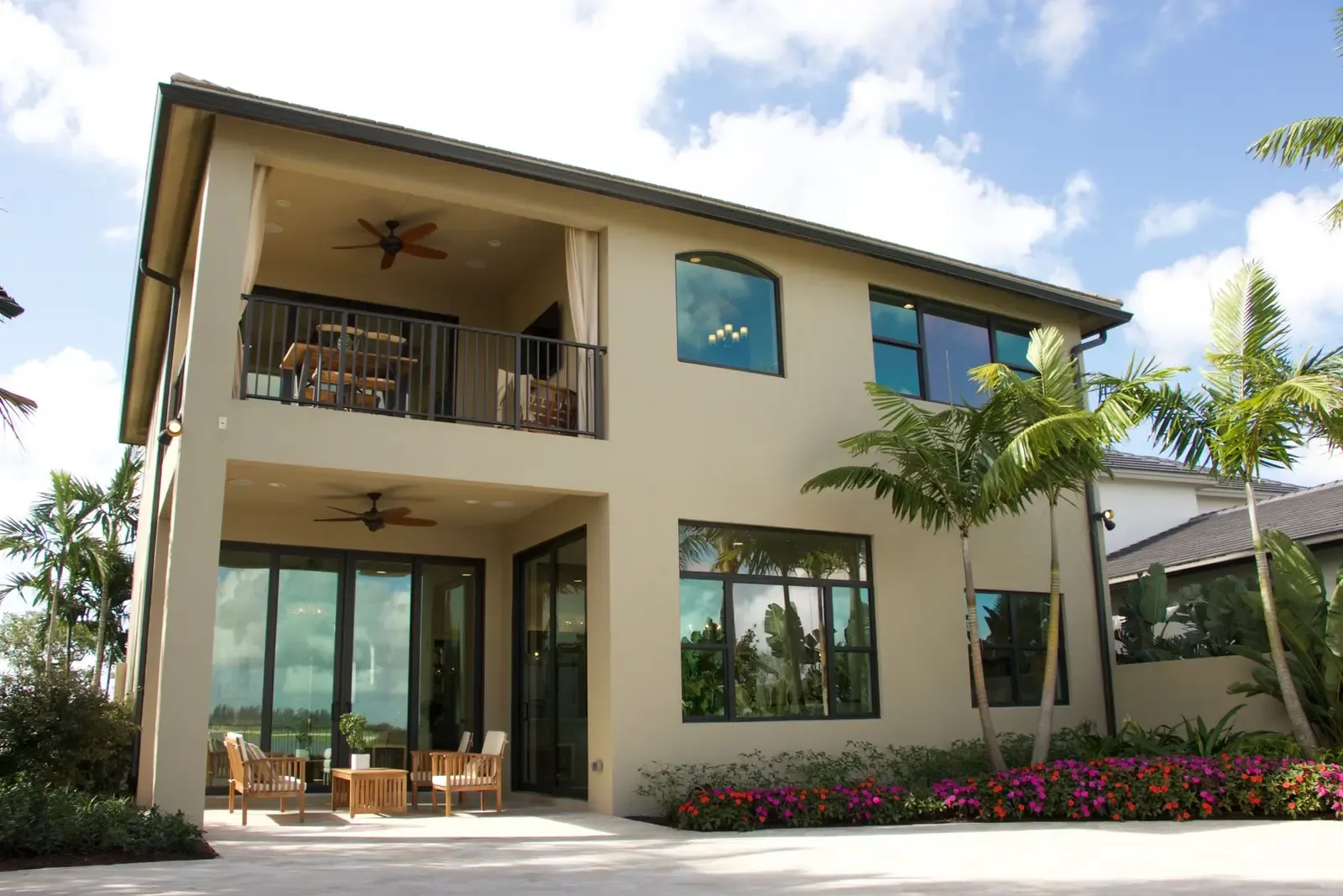 Two-story stucco home with a covered patio and palm trees in the yard